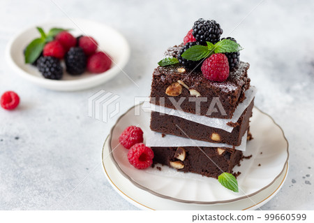 chocolate brownie square pieces with raspberries and blackberries 99660599