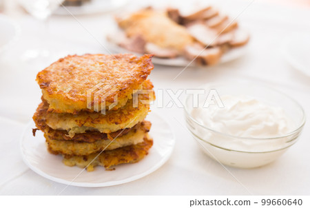 Potato pancakes with sour cream on white plate Potato pancakes with sour cream on white plate 99660640