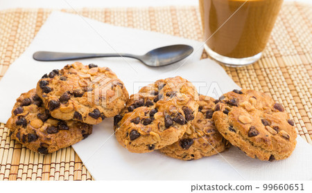 cookies with chocolate and hazelnuts and coffee with milk lie on the table cookies with chocolate and hazelnuts and coffee with milk lie on the table 99660651