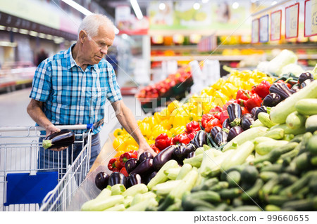 Elderly retired man buying eggplants in grocery section of the supermarket Elderly retired man buying eggplants in grocery section of the supermarket 99660655