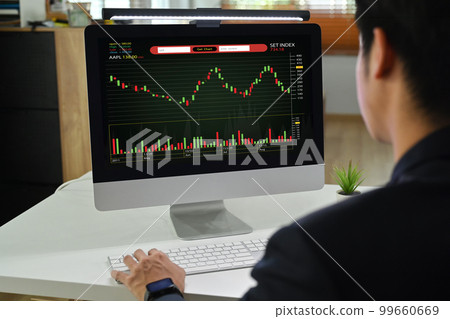 Rear view of man trader investor analyzing digital exchange stock market charts graphs on computer screen 99660669