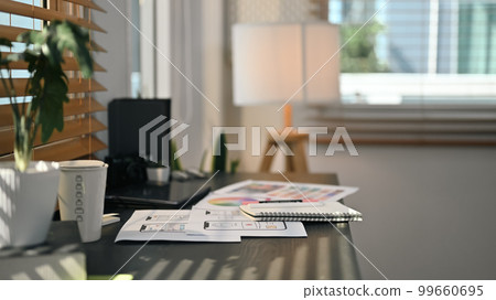 Creative office interior with digital tablet and wireframe sketches for mobile application on black wooden table Creative office interior with digital tablet and wireframe sketches for mobile application on black wooden table 99660695