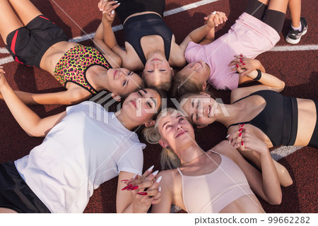 Group of girls resting on floor at stadium 99662282