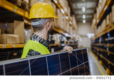Rear view of warehouse worker carring solar panel. Rear view of warehouse worker carring solar panel. 99662731