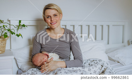 Mother brestfeeding her little newborn baby in their bedrooom. Mother brestfeeding her little newborn baby in their bedrooom. 99662861