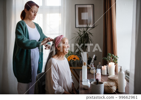 Caregiver helping her client with a hairstyle. 99662961