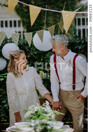 Mature bride and groom having a romantic moment at wedding reception outside in the backyard. Mature bride and groom having a romantic moment at wedding reception outside in the backyard. 99663135