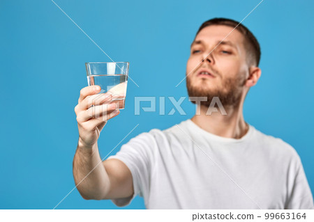Young handsome man with drinking glass of water smiling happy 99663164