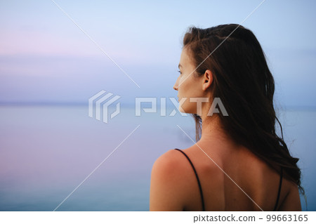 Rear view of young beautiful sportive girl standing by the lake on early morning and contamplating. 99663165