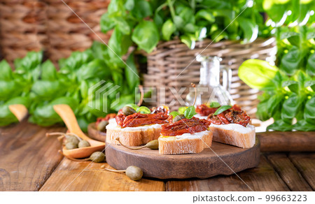 Bruschetta with sun-dried tomatoes, cheese, basil and capers. Traditional appetizer for aperitivo in 99663223