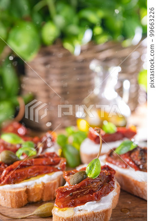 Bruschetta with sun-dried tomatoes, cheese, basil and capers. Traditional appetizer for aperitivo in 99663226