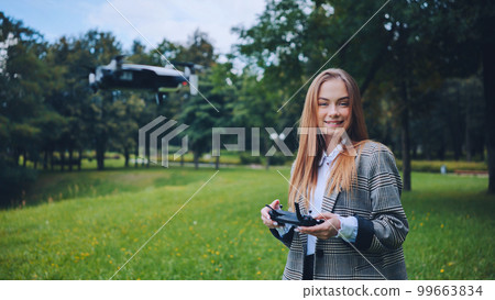 A cute girl controls a drone in the park. A cute girl controls a drone in the park. 99663834