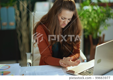 business owner woman in green office experience carpal syndrome 99663977