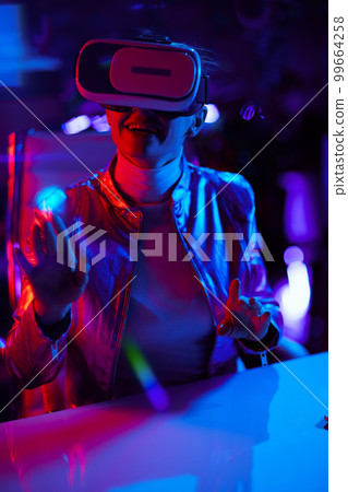 smiling female using virtual reality technology in office 99664258