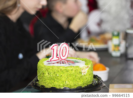 Festive cake with the number ten on the background of blurry guests. Festive cake with the number ten on the background of blurry guests. 99664515