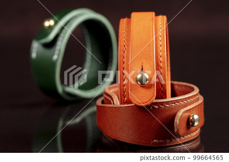 Leather bracelets with metal details on a dark background. Leather bracelets with metal details on a dark background. 99664565