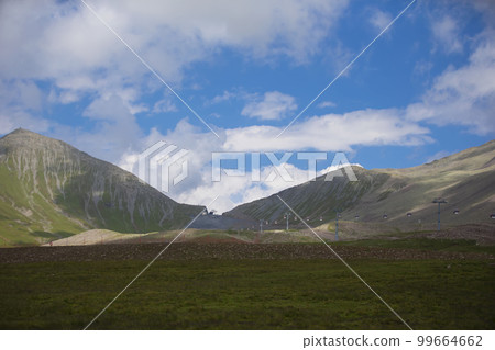 Summer mountain landscape and a cable car in the distance. 99664662