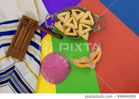 On Purim, Jewish holiday people traditionally enjoy eating hamantaschens, blowing shofars, wearing tallits participating in festivities with carnival masks. On Purim, Jewish holiday people traditionally enjoy eating hamantaschens, blowing shofars, wearing tallits participating in festivities with carnival masks. 99664899