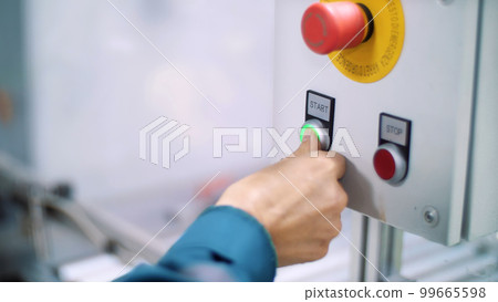 close-up, on a special shield, the hand presses the green start button, next to the red-stop 99665598