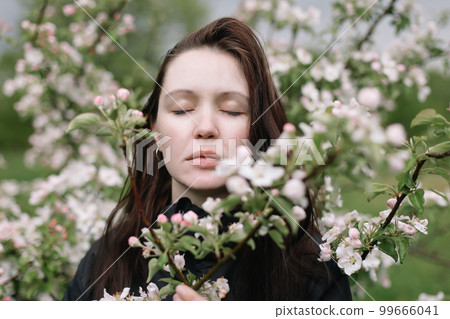Woman with natural makeup, floral cosmetics for skin of the face, girl posing in flower branches of blooming apple tree in spring Woman with natural makeup, floral cosmetics for skin of the face, girl posing in flower branches of blooming apple tree in spring 99666041