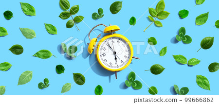 Yellow vintage alarm clock with green leaves 99666862