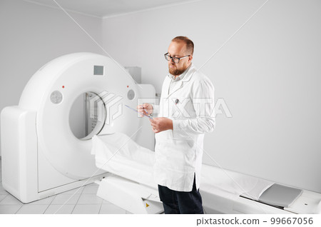 Portrait of doctor with medical computed tomography or MRI scanner. Radiologist holding and examining results of MRI. Concept of medicine, healthcare and modern diagnostics. Portrait of doctor with medical computed tomography or MRI scanner. Radiologist holding and examining results of MRI. Concept of medicine, healthcare and modern diagnostics. 99667056