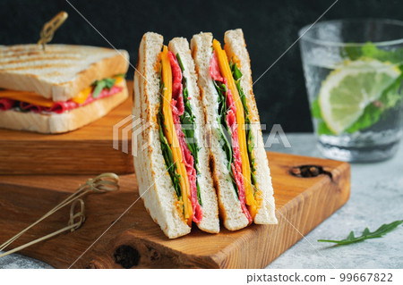 Two homemade sandwiches with sausage, cheese and arugula on a light concrete background 99667822