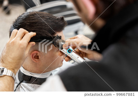 Barber shaving caucasian man in barber shop. 99667881