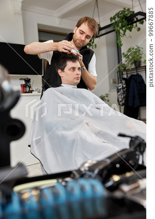 Hairstylist serving handsome man in barber shop. 99667885