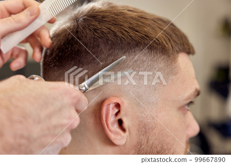 hairdresser does haircut for caucasian bearded man 99667890