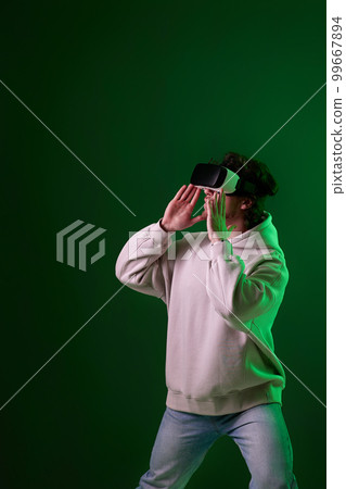 man in vr glasses and sweatshirt plays on blue background. 99667894