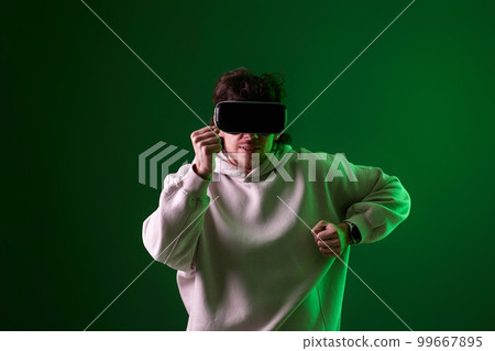 man in vr glasses and sweatshirt plays on blue background. 99667895