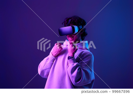 man in vr glasses and sweatshirt plays on blue background. man in vr glasses and sweatshirt plays on blue background. 99667896
