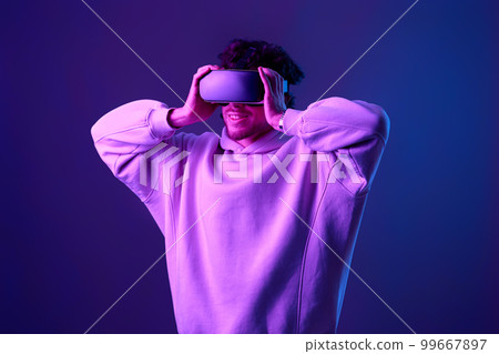 man in vr glasses and sweatshirt plays on blue background. 99667897