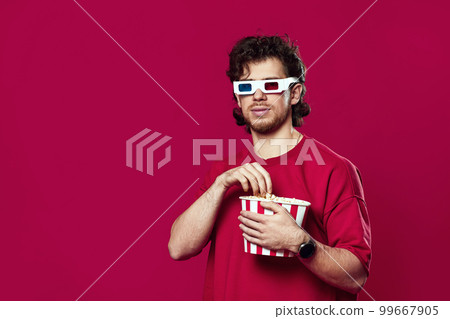 man in 3d glasses holding big bucket of popcorns 99667905