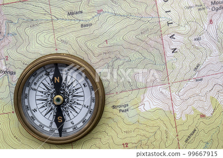 Topographical map showing contour lines with compass laid on top, flat lay. High quality photo 99667915