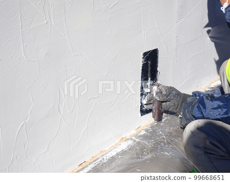 A trowel is being applied to prevent the spalling of a concrete structure 99668651
