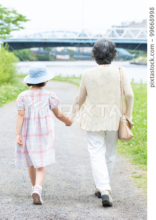 girl and grandma walking hand in hand 99668998