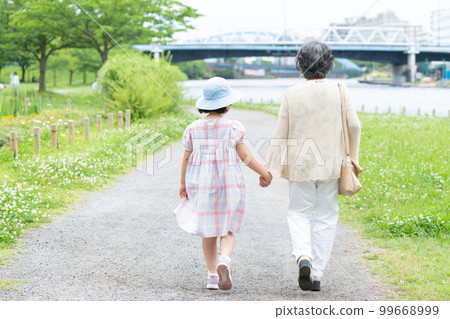 girl and grandma walking hand in hand girl and grandma walking hand in hand 99668999