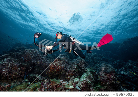 Scuba diver with camera diving over coral reef in Thailand 99670023