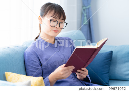 Woman with glasses reading a book on the sofa Woman with glasses reading a book on the sofa 99671052