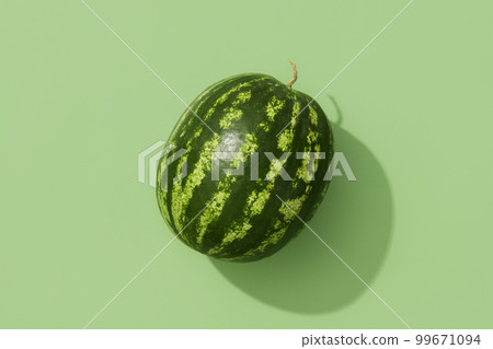 Flat lay top view whole watermelon in sunlight. Fruit on green background Flat lay top view whole watermelon in sunlight. Fruit on green background 99671094