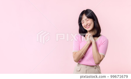 Adorable young happy asian woman model with shy emotion smiling expression cheerful positive attractive face and holding hand isolated on pink pastel studio background. Portrait beautiful cute lady. 99671679
