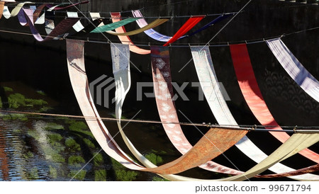 On the dyeing path, the dyed goods displayed along the river are in a gentle breeze. On the dyeing path, the dyed goods displayed along the river are in a gentle breeze. 99671794