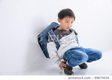 A boy looking down while carrying a school bag A boy looking down while carrying a school bag 99674036