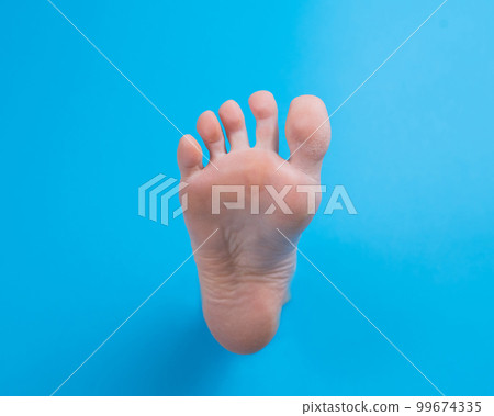 Female bare foot on a blue background. Female bare foot on a blue background. 99674335