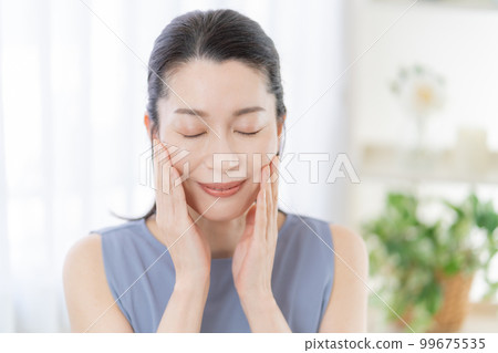 中年婦女撫摸著她的皮膚，微笑著 99675535