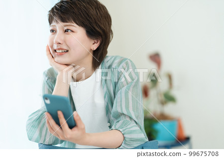 A young woman operating a smartphone 99675708