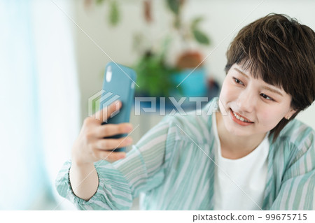 A young woman operating a smartphone A young woman operating a smartphone 99675715