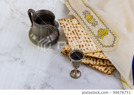 Traditional Passover food consists of unleavened matzah bread and kosher kiddush cup wine during Pesach 99676751